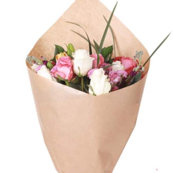 Bouquet of pink and white roses wrapped in tan paper