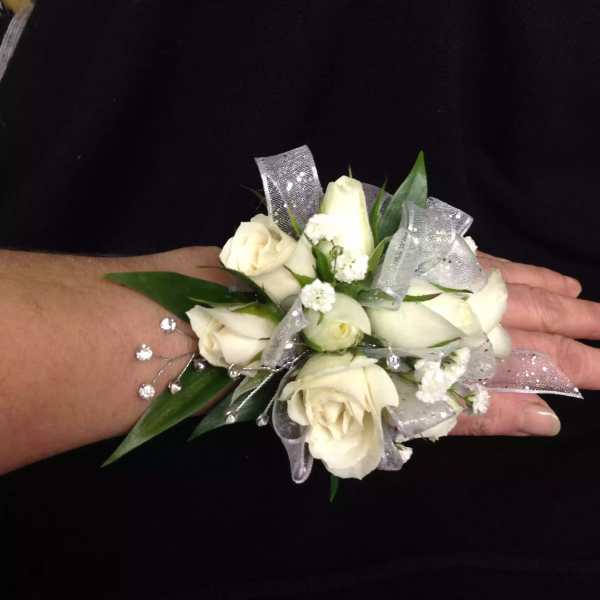 White rose wrist corsage with silver ribbon on a person's wrist