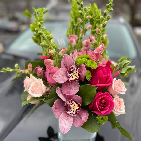 Pink orchids and roses arranged in a bouquet with green accents