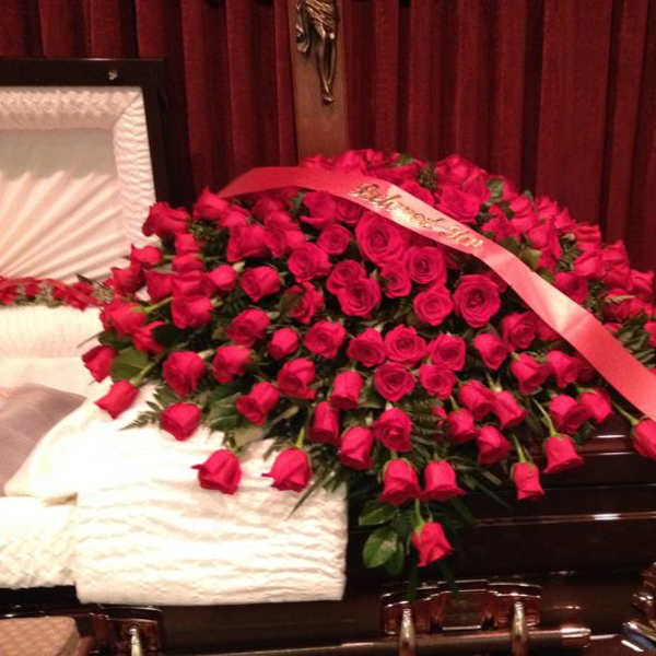 Large bouquet of red roses with a pink ribbon draped across it