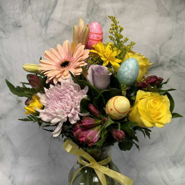 Mixed bouquet in a glass vase with pastel flowers and decorative eggs