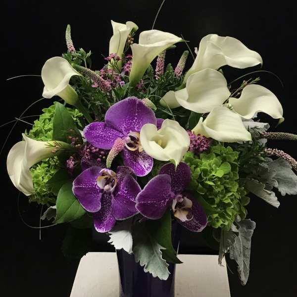 Purple orchids and white calla lilies in a dark vase