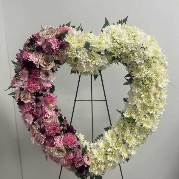 Heart-shaped floral wreath with pink and white flowers on a stand