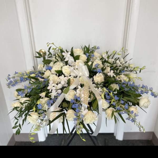 Large white and blue floral spray with ribbon on a stand