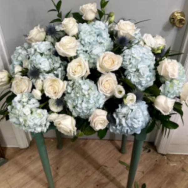 Blue hydrangeas and white roses arranged on a small table.