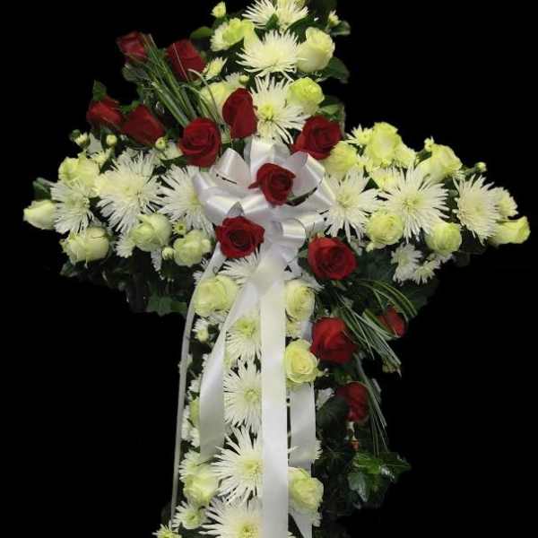 Cross-shaped floral spray with red roses, white chrysanthemums, and white ribbon