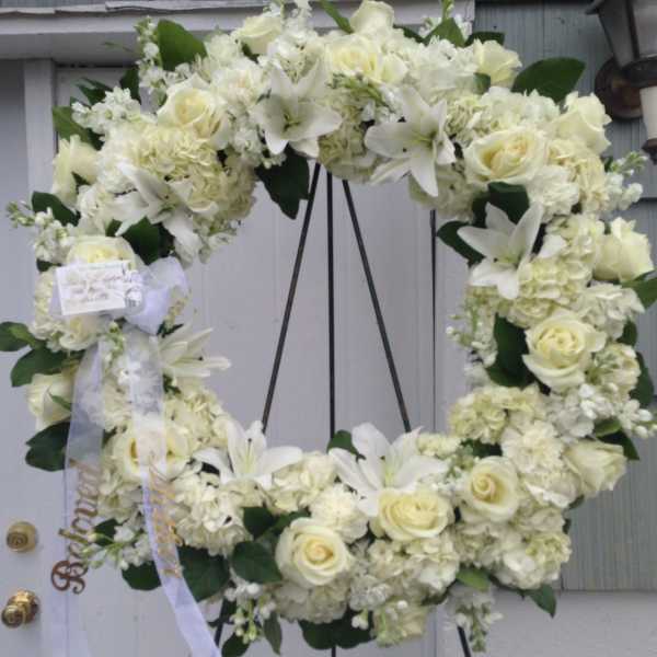 White floral wreath with roses and lilies on a stand