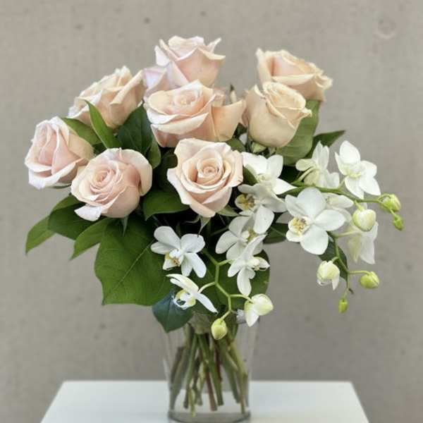 Blush roses and white orchids in a clear glass vase