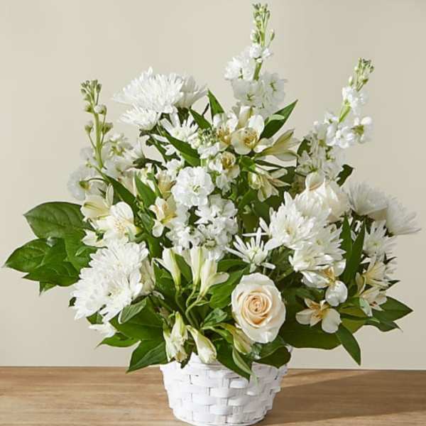 White and cream flowers including roses and mums arranged in a white woven basket