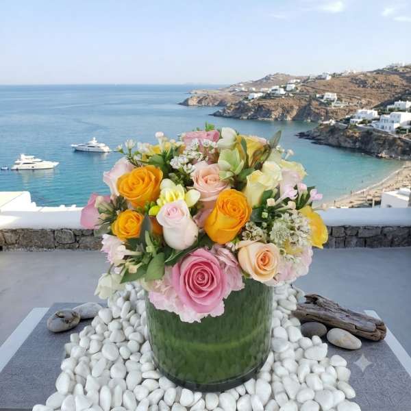Mixed pastel roses arranged in a green glass vase with white stones