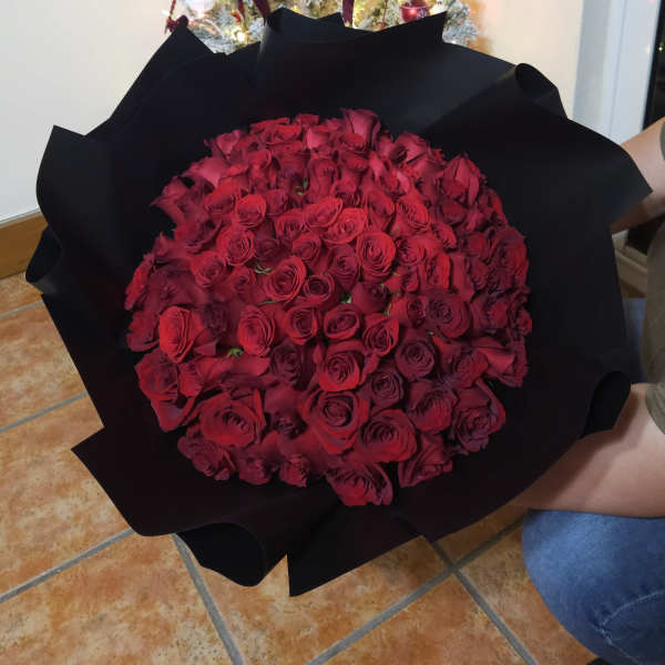 Large bouquet of red roses wrapped in black paper