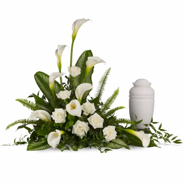 White calla lilies and roses arranged beside a white urn