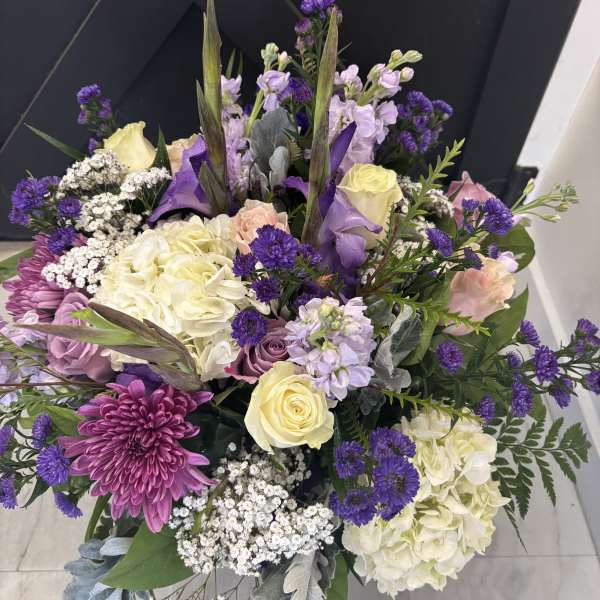Bouquet of purple, cream, and pink flowers with tall greenery