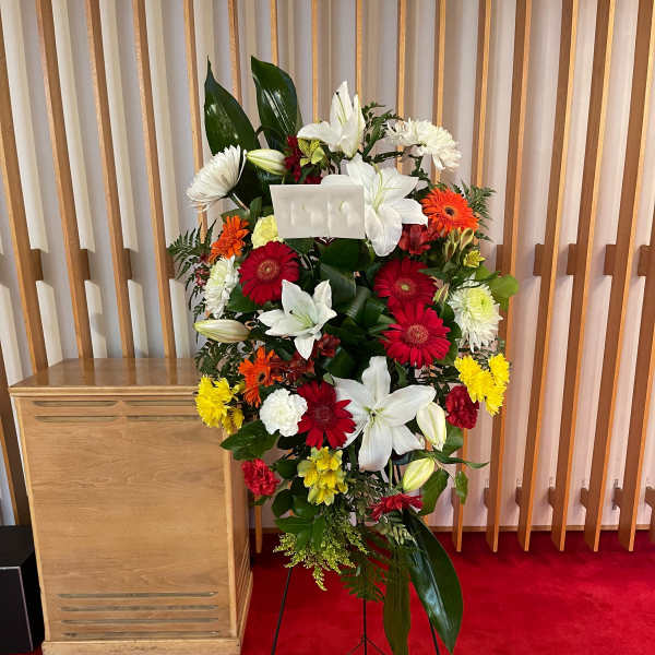 Standing floral spray with white lilies, red gerberas, and yellow blooms