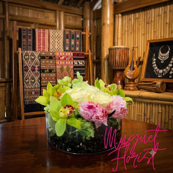 Low glass bowl with pink and white flowers and green orchids