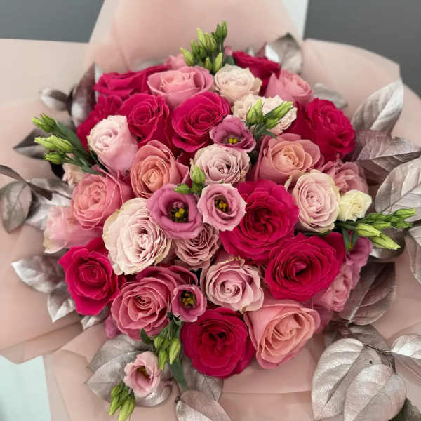Bouquet of pink and red roses with pale wrapping and metallic leaves