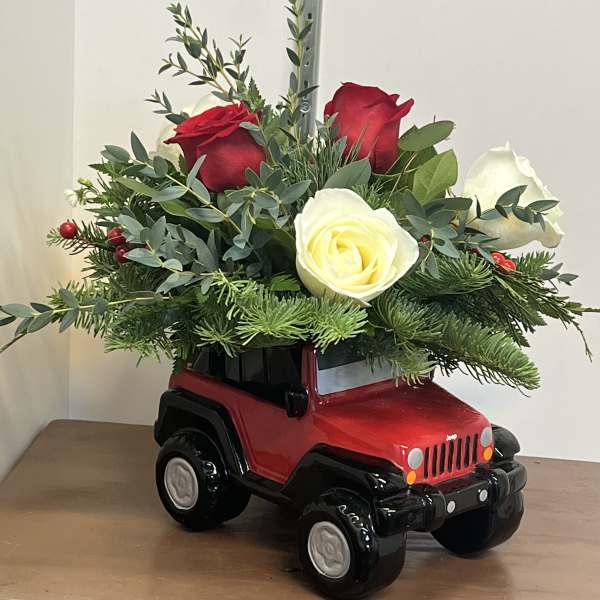 Red and white roses arranged in a red toy Jeep planter