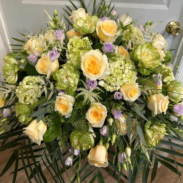 Large floral spray with cream roses, green blooms, and lavender accents