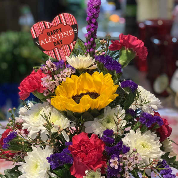Mixed flower arrangement in a heart-decorated pot with a Valentine sign