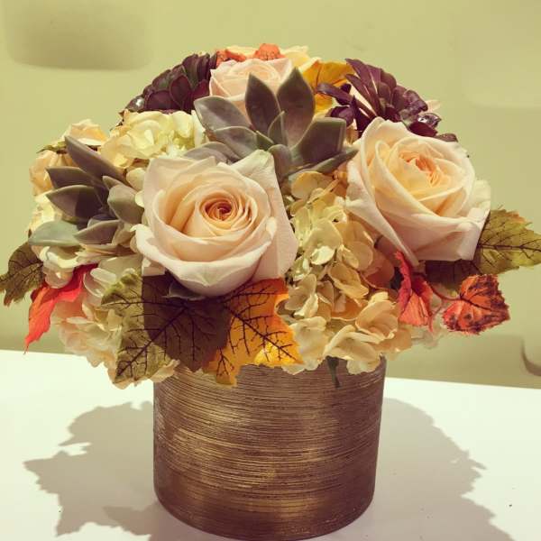 Peach roses and succulents in a textured brown vase
