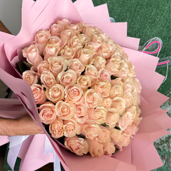 Large bouquet of pale peach roses wrapped in pink paper
