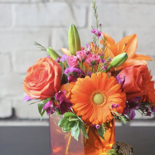 Orange roses and gerbera daisies in a glass vase