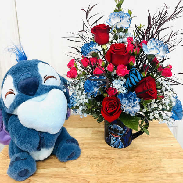 Bouquet of red roses and blue carnations in a Stitch mug beside a plush Stitch toy