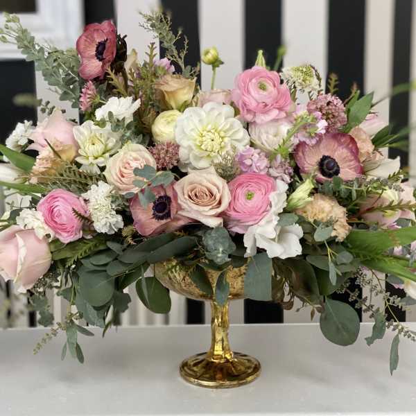 Pink and white mixed flower arrangement in a gold pedestal vase