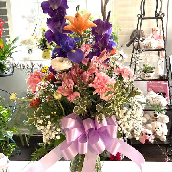 Mixed bouquet in a glass vase with a pink ribbon