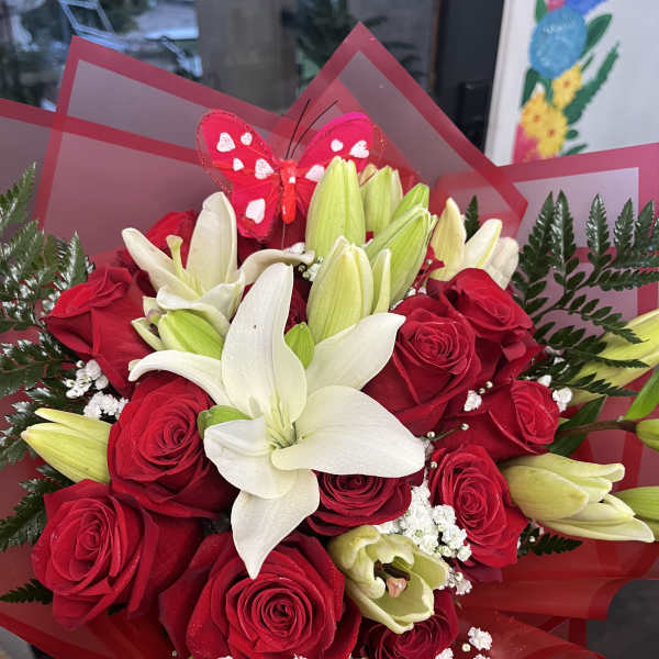 Bouquet of red roses and white lilies wrapped in red paper