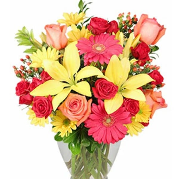 Colorful bouquet of roses, gerbera daisies, and lilies in a glass vase
