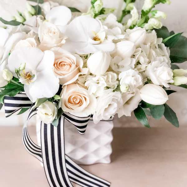 White floral arrangement with pale peach roses in a white vase