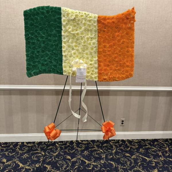 Floral tribute in green, white, and orange arranged on an easel