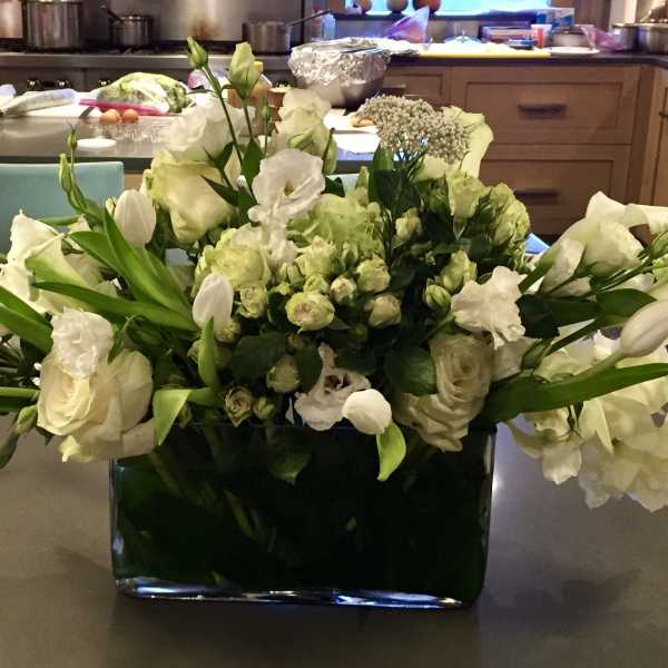 White floral arrangement in a dark rectangular vase on a countertop