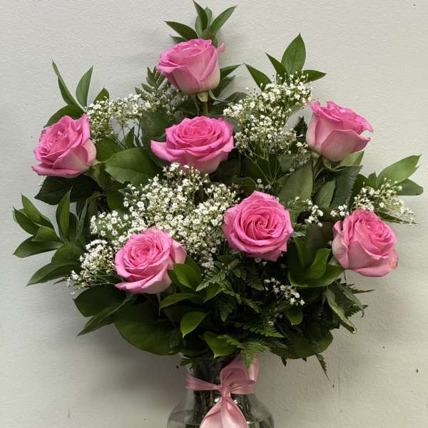 Pink roses arranged in a clear glass vase with baby's breath