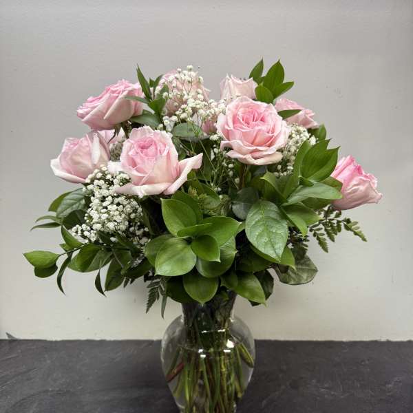 Pink roses in a clear glass vase with white filler flowers