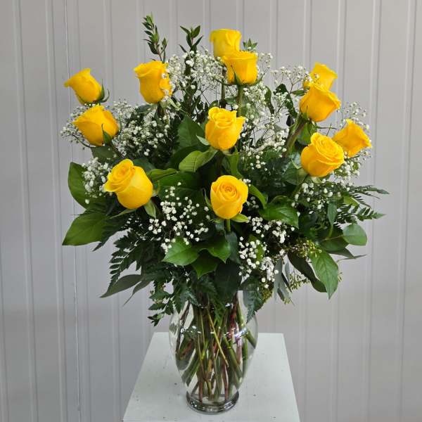 Yellow roses in a clear glass vase with white baby's breath