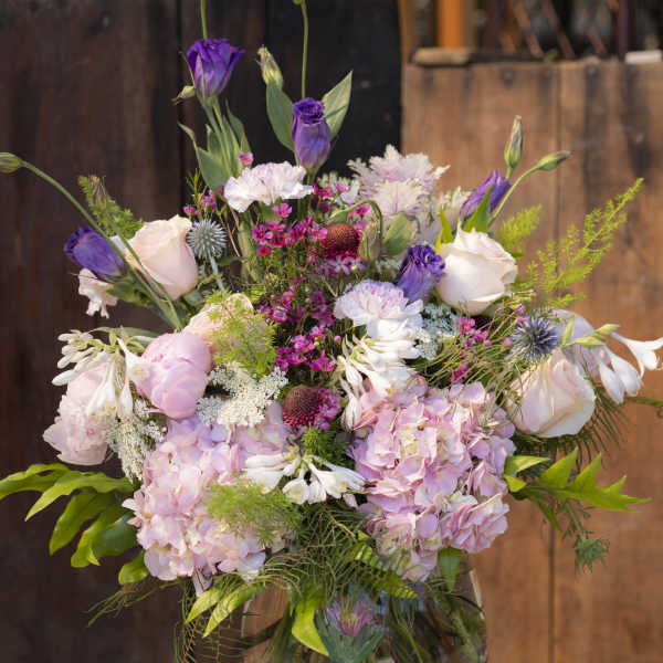 Mixed pink and purple flower arrangement in a glass vase