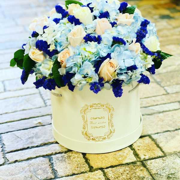 Blue and cream flower arrangement in a round white box