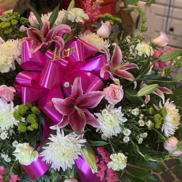 Pink and white floral arrangement with a bright magenta ribbon bow