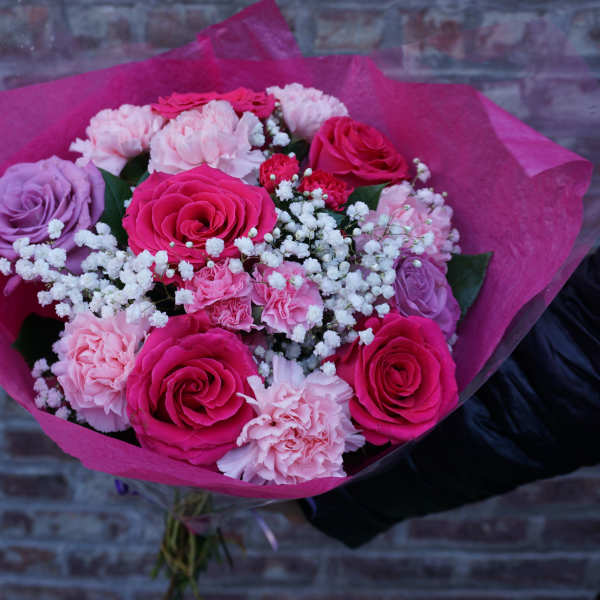 Bouquet of pink and lavender roses with carnations in bright pink wrap
