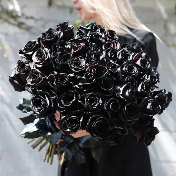 Large bouquet of black roses held by a person in dark clothing
