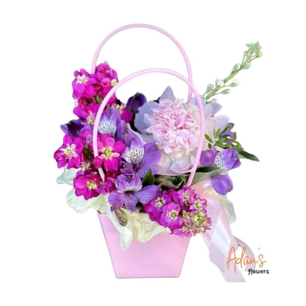 Pink basket arrangement with purple and pink flowers and a ribbon