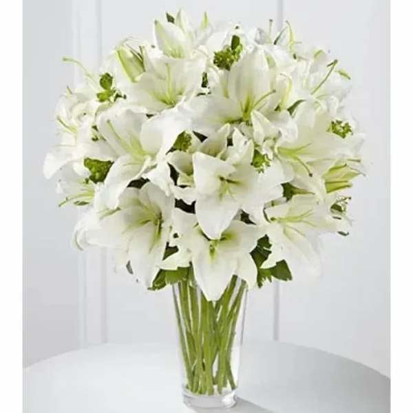 Tall arrangement of white lilies in a clear glass vase