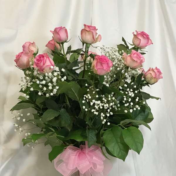 Pink roses with baby's breath in a clear glass vase tied with a pink bow