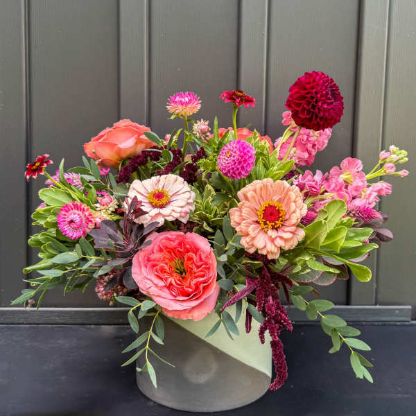 Low arrangement of pink and peach mixed flowers in a round ceramic vase