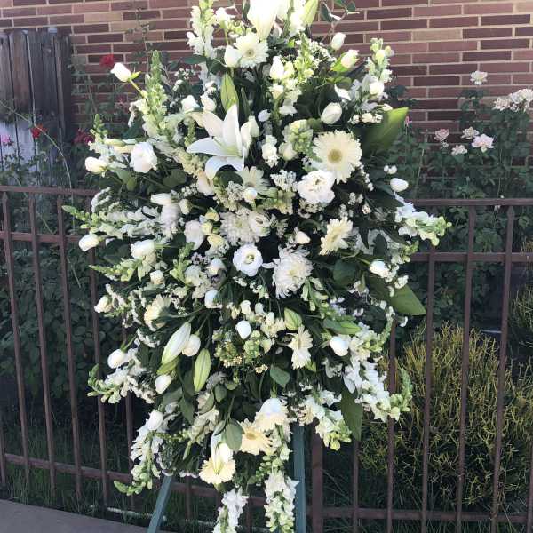 Large white funeral spray on an easel with lilies and daisies