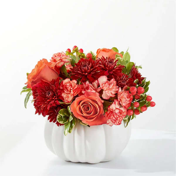 Orange roses and red chrysanthemums in a white pumpkin vase