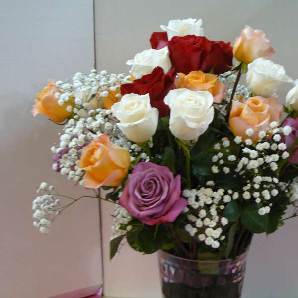 Mixed roses in a clear glass vase with baby's breath