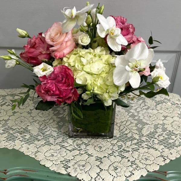 Pink and white floral arrangement in a square glass vase